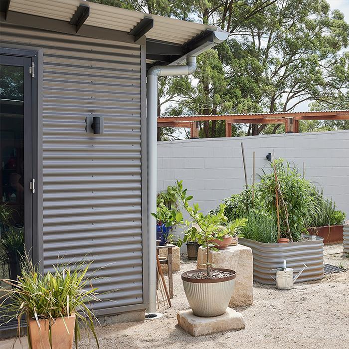 Backyard with plants and home exterior featuring grey Lysaght corrugated cladding.