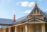 Heritage stone home with CUSTOM ORB® roofing, showcasing a blend of traditional architecture and modern roofing solutions under a sunny sky.