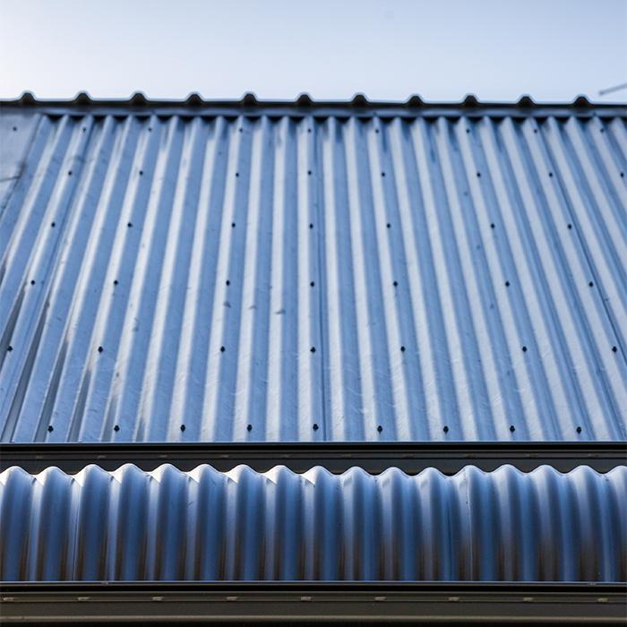 Close-up of CUSTOM ORB® corrugated steel roofing, highlighting its iconic profile under a blue sky. 