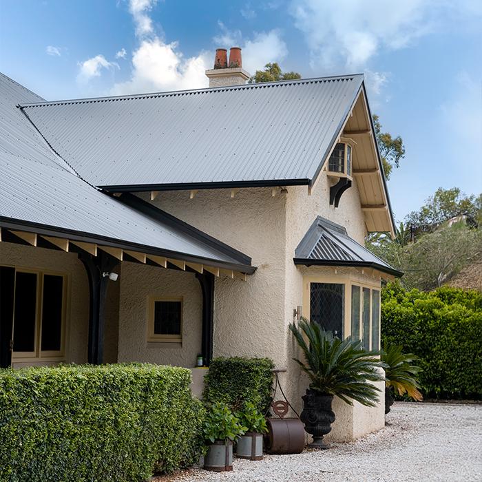 Heritage home featuring CUSTOM ORB® roofing, blending traditional design with natural surroundings.