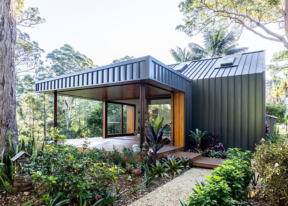 Contemporary home with Lysaght house cladding and timber accents, set in lush surroundings 